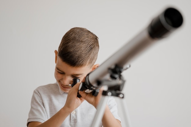 Free Photo boy using a telescope in class