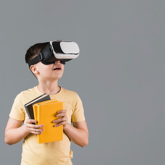 Boy using virtual reality headset while holding books