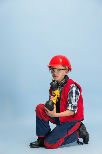 Free photo boy wearing red helment and holding drill