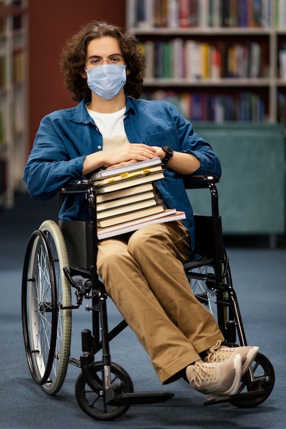 Free Photo boy in wheelchair holding a bunch of books