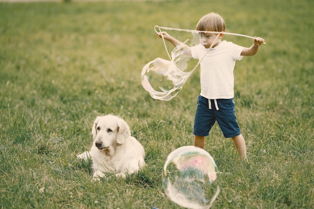 Free photo boy with blonde hair making a giant soap bubbles. boy wearing white t-shirt and blue shorts