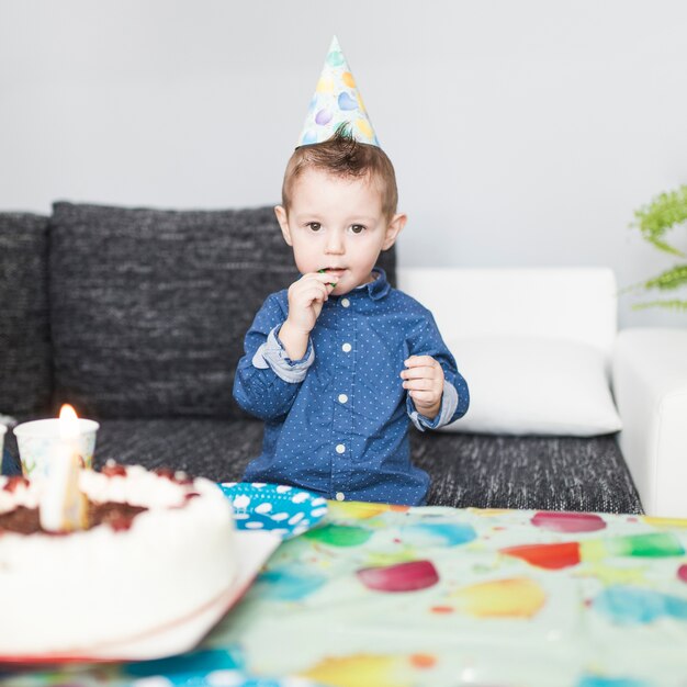 Boy with lollipop near cake