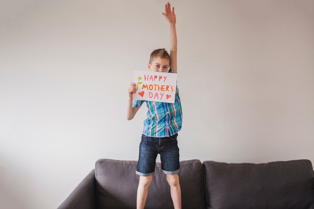 Boy with mother's day poster and raised arm