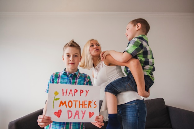 Free photo boy with mother's day poster with his brother and his mother in the background