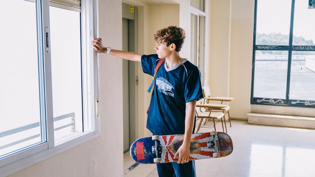 Free photo boy with skateboard looking through window