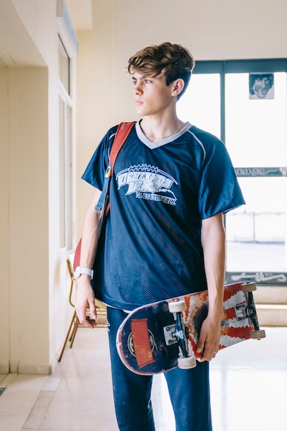 Boy with skateboard in school buidling