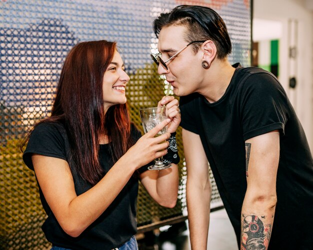 Boyfriend drinking drinks from straw hold by her girlfriend