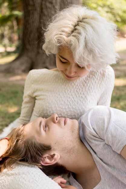 Boyfriend relaxing on girlfriend's lap while outdoors