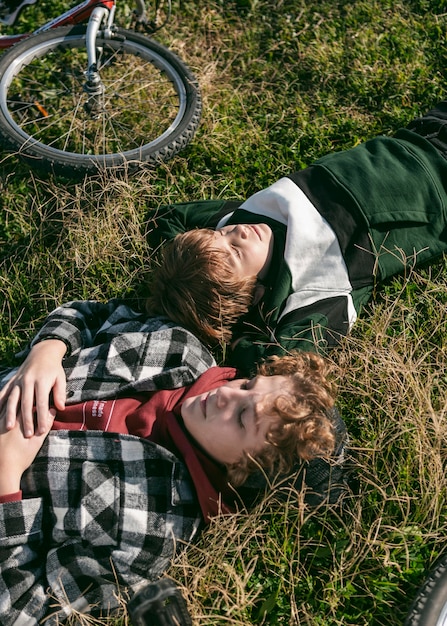 Free photo boys resting on grass while riding their bikes