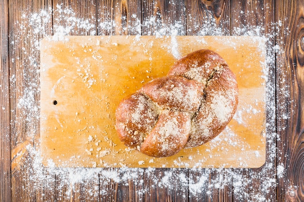 Braided bread on chopping board with spread white flour