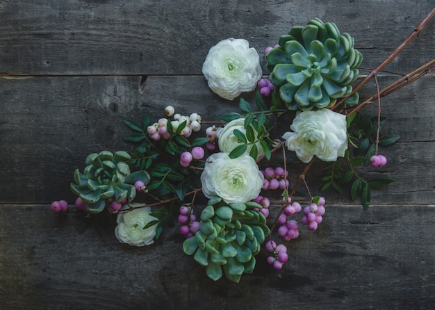 A branch of white and purple blossom flowers on a wooden table.