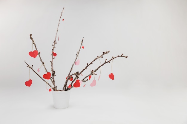 Free Photo branches of a plant in a white flowerpot with hanging hearts