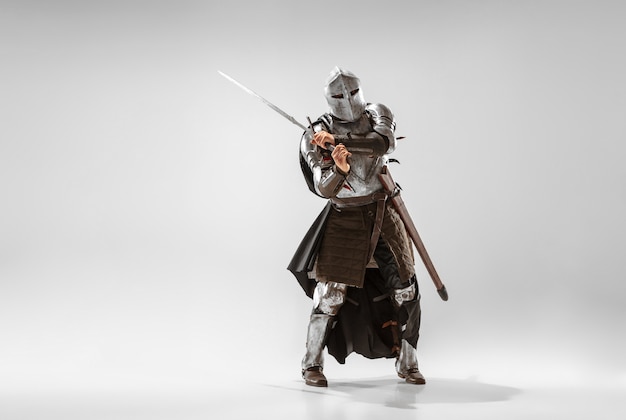 Brave armored knight with professional weapon fighting isolated on white studio background. Historical reconstruction of native fight of warriors. Concept of history, hobby, antique military art.