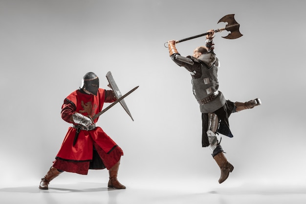 Brave armored knights with professional weapon fighting isolated on white studio background. Historical reconstruction of native fight of warriors. Concept of history, hobby, antique military art.