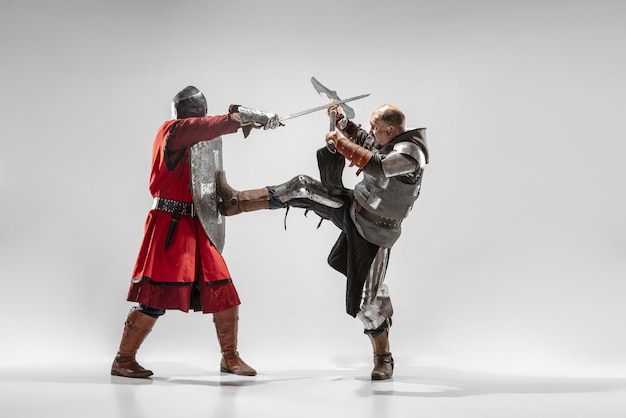 Free photo brave armored knights with professional weapon fighting isolated on white studio background.