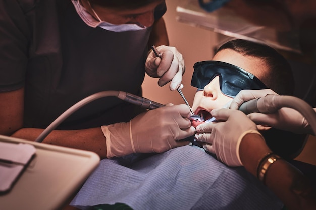 Brave small child gets a dental treatment by expirienced doctor at dental clinic.