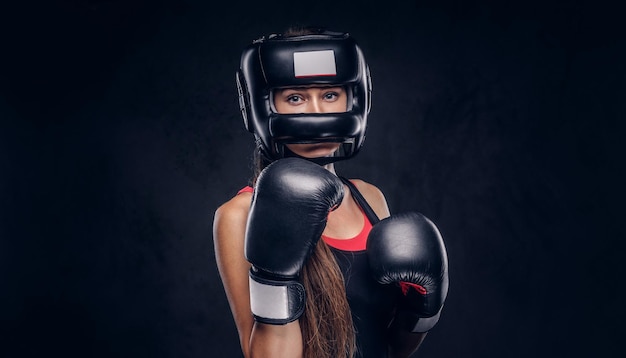 Brave woman is ready to fight, she is wearing boxer gloves and protective helmet.