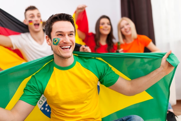 Brazilian man with friends from different country enjoying the soccer on TV