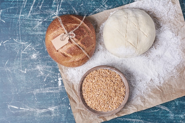 Free photo bread bun with dough and wheat on blue table.