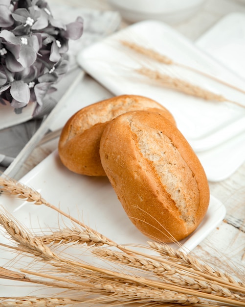 Free photo bread buns with wheat branch on the table