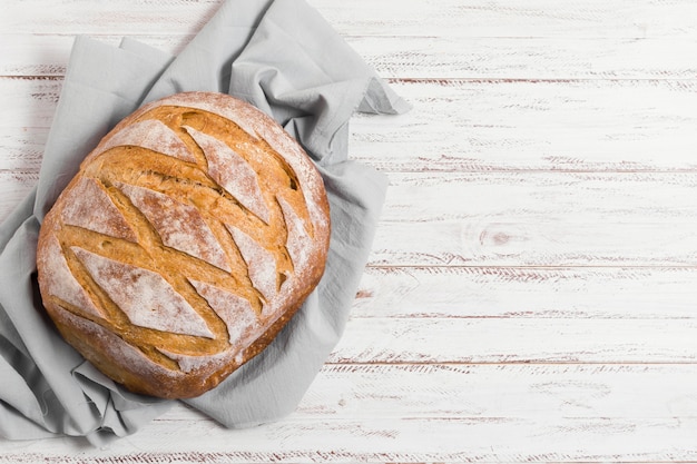 Bread on kitchen cloth and wooden background top view