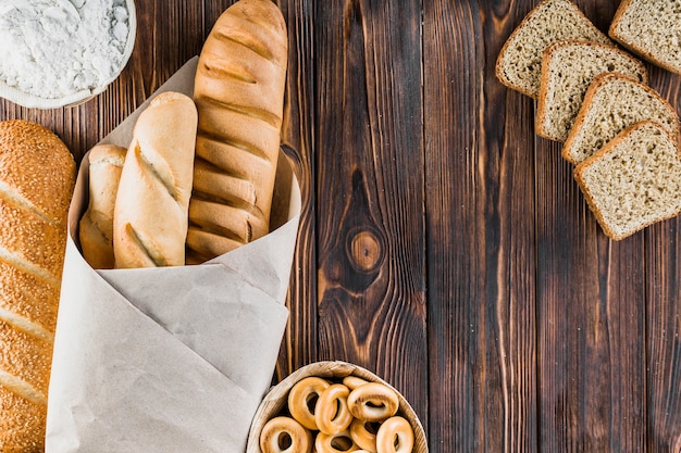 Bread slice, baguettes, bagels, flour on the wooden backdrop