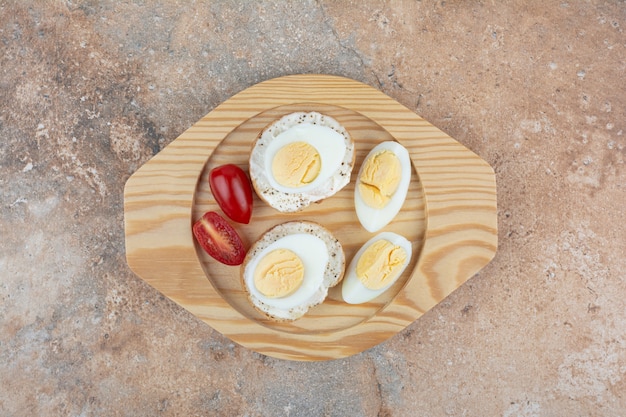 Free photo bread slices with boiled eggs and tomatoes on wooden plate