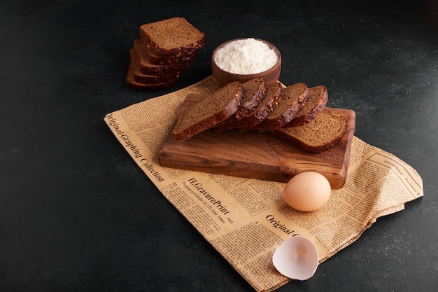 Bread slices with ingredients on the piece of newspaper. 