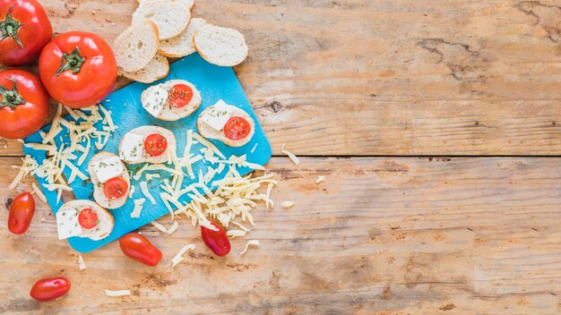 Free Photo bread slices with tomatoes and grated cheese on wooden table