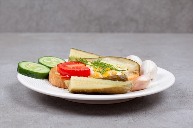 Bread with scrambled egg and pickles on white plate