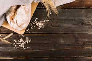 Free photo bread with sunflower seeds and wheat crop on wooden table