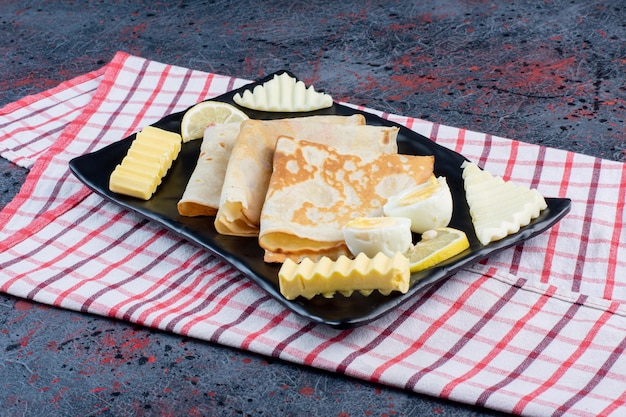 Breakfast board with crepes, cheese, lemon and eggs. 