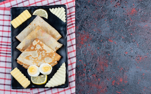 Free Photo breakfast board with crepes, cheese, lemon and eggs. 