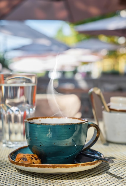 Free Photo breakfast in a cafe vertical shot steam rises over a cup of espresso coffee glass of water and cookies on the table closeup sunlight and selective focus empty space idea for advertising or banner