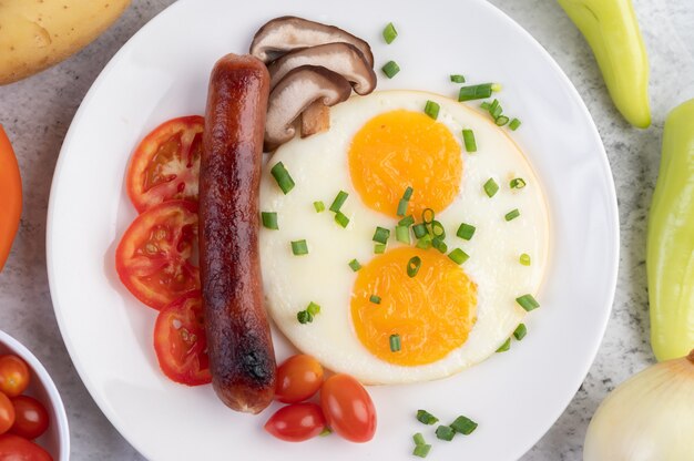 Breakfast consisting of bread, fried eggs, tomatoes, Chinese sausage and mushrooms.