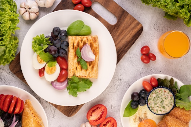 Free photo breakfast consists of bread, boiled eggs, black grape salad dressing, tomatoes, and sliced ââonions.