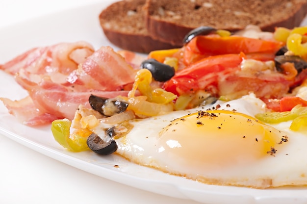 Breakfast - fried eggs with bacon, tomatoes, olives and slices of cheese