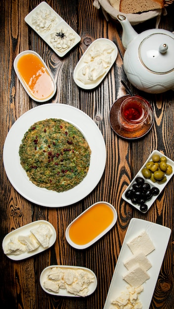 Breakfast set of cheeses, honey, tea and a azeri traditional kyukyu with pomegranate