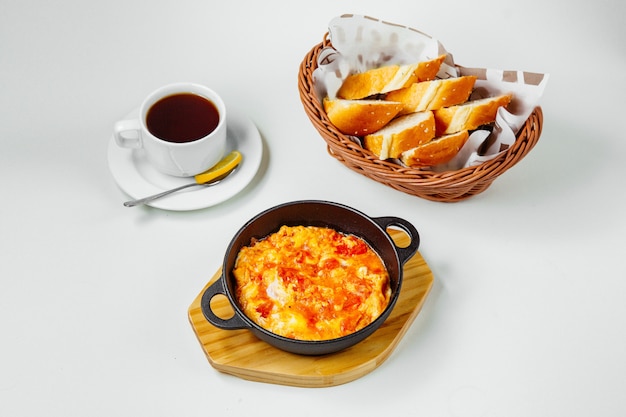 Breakfast setup with egg and tomato dish black tea and bread