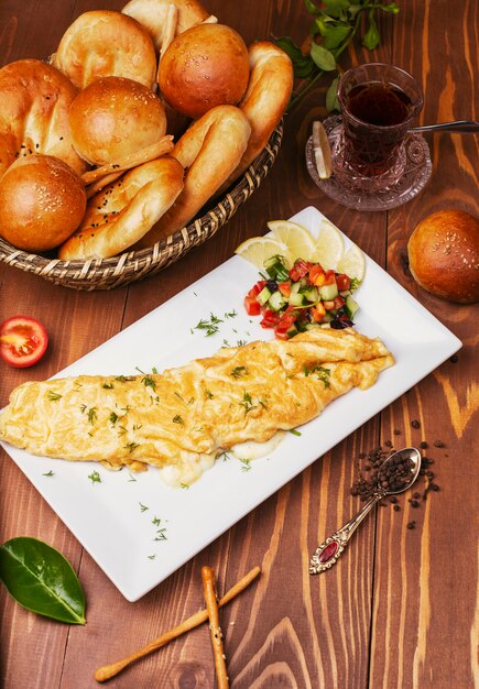 Breakfast snack crepes, omlettes with vegetable salad and bread buns in white plate