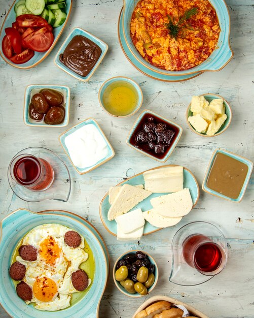 Breakfast table of different types of fried eggs cheeses honey chocolates and tea