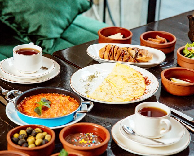 Breakfast table with cups of tea olives and omelet