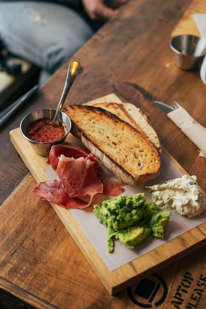 Breakfast toast with ham and avocado on board