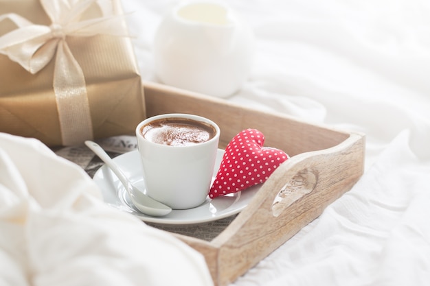 Breakfast tray with a coffee, a heart and a golden gift