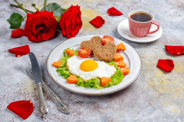 Breakfast on Valentine's Day - fried eggs and bread in the shape of a heart and fresh vegetables.