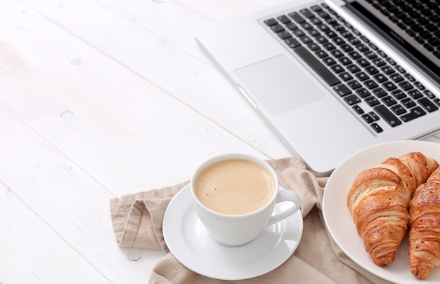 Free photo breakfast with croissants and coffee near a laptop