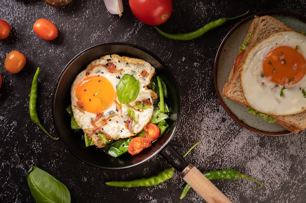 Free photo breakfast with fried eggs, sausage, and ham in a pan with tomatoes. chili and basil.