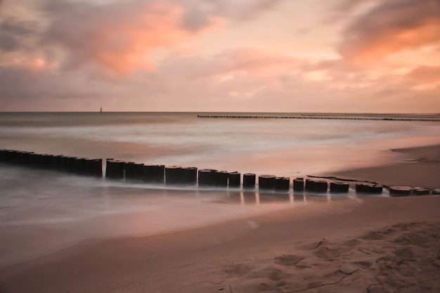 Free Photo breakwater in the sandy beach during the sunset