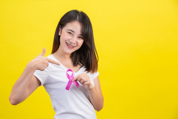 Free photo breast cancer , a woman in a white t-shirt with a satin pink ribbon on her chest, a symbol for breast cancer awareness