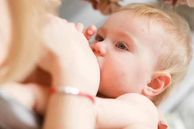 Breastfeeding blonde baby. Close-up head portrait